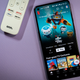 A photo of an Android device with Netflix on as the main event, with a remote off to the side with a Netflix shortcut on it